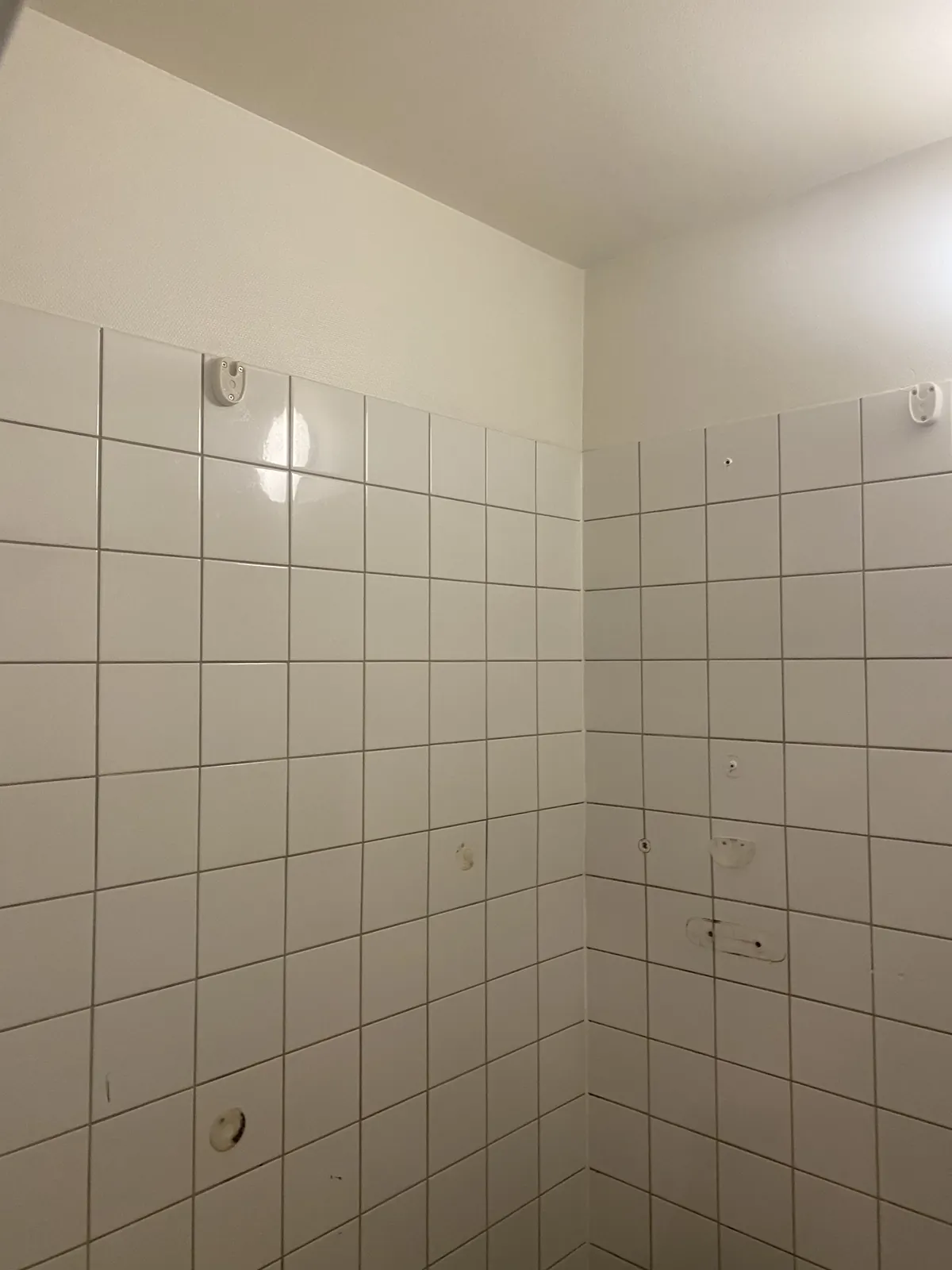Badet før: hvite fliser fra gulv til midt på veggen.